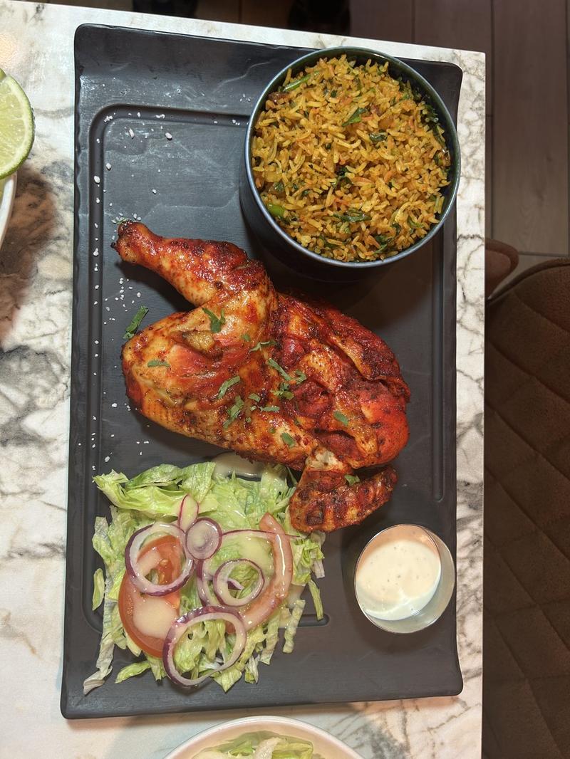 Poulet tandoori grillé, riz épicé et salade fraîche sur ardoise
